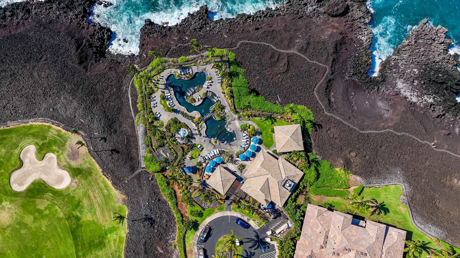 Aerial view of an oceanfront resort set against the black lava coastline of Hawaiʻi Island