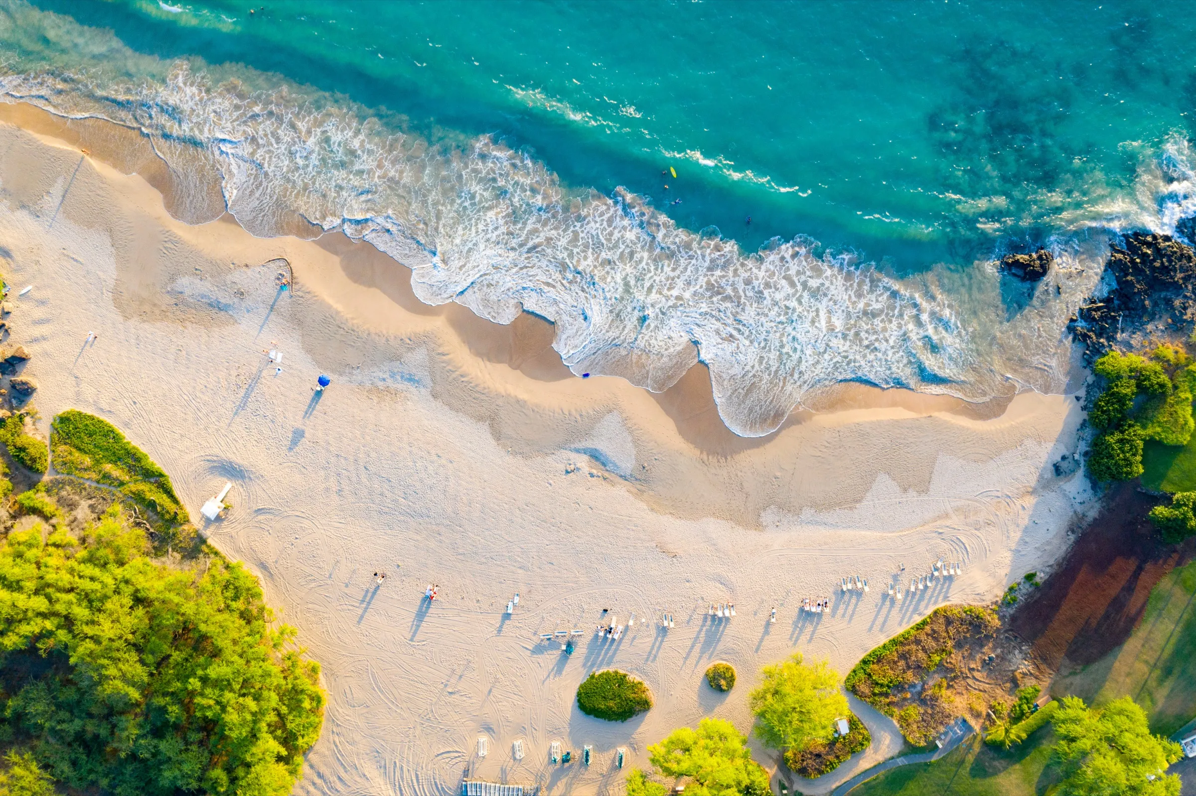 Aerial view of white sand meeting turquoise surf on a Hawaiʻi Island beach